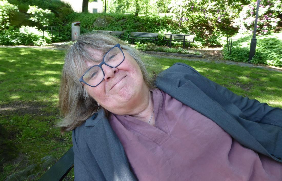 Iris Alfredsson i en grönskande park med bänkar i bakgrunden.