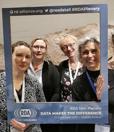Foto på fyra konferensdeltagare som håller upp en stor ram runt sig med tryckt text på om RDA-mötet i Helsingfors 2019.